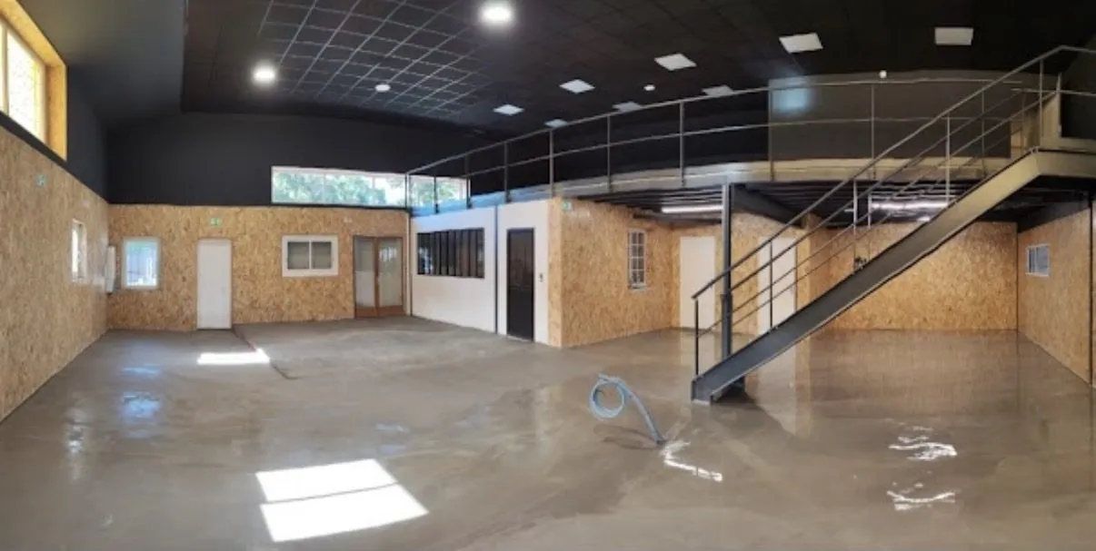 Vue d'ensemble d'un local professionnel aménagé : mezzanine, escalier métallique, habillage des murs et sol en résine