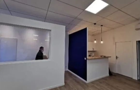 Bureau cloisonné avec verrière intérieure, mur bleu et coin cuisine d'entreprise avec comptoir et suspensions