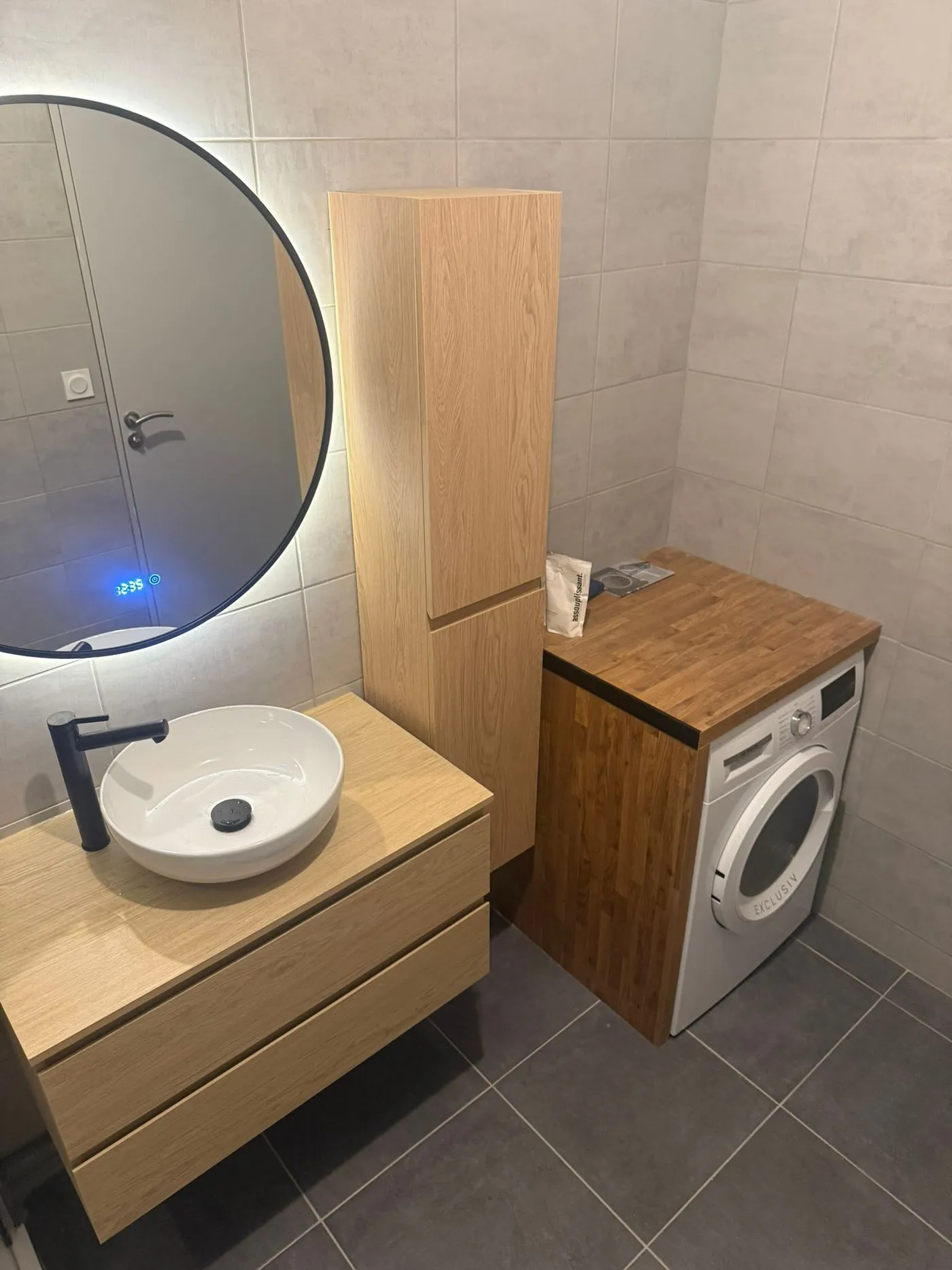 Salle de bains avec meuble vasque en chêne, colonne de rangement et lave-linge habillé d'un plan de travail bois