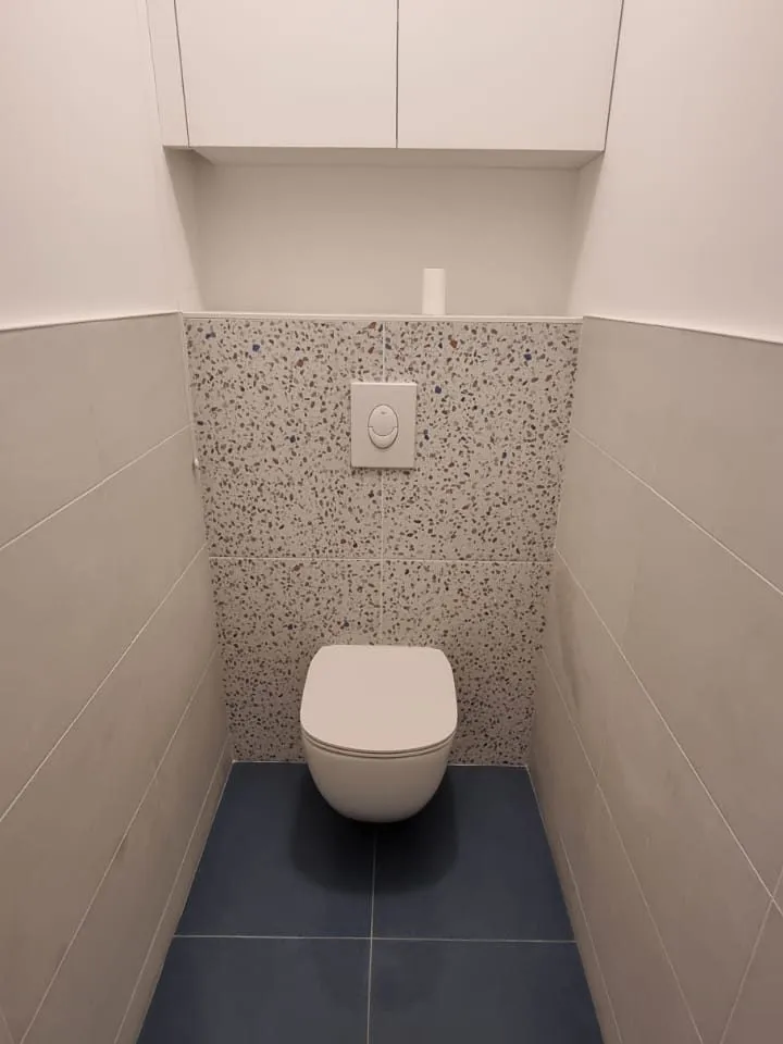 WC suspendu avec coffrage carrelé en terrazzo, meubles hauts et sol en carrelage bleu